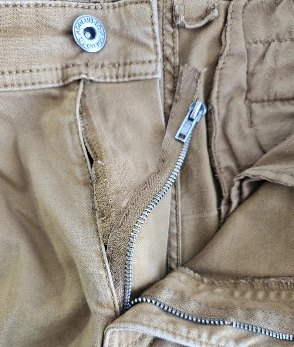Avant la retouche : braguette d'un pantalon beige encore bâtie
